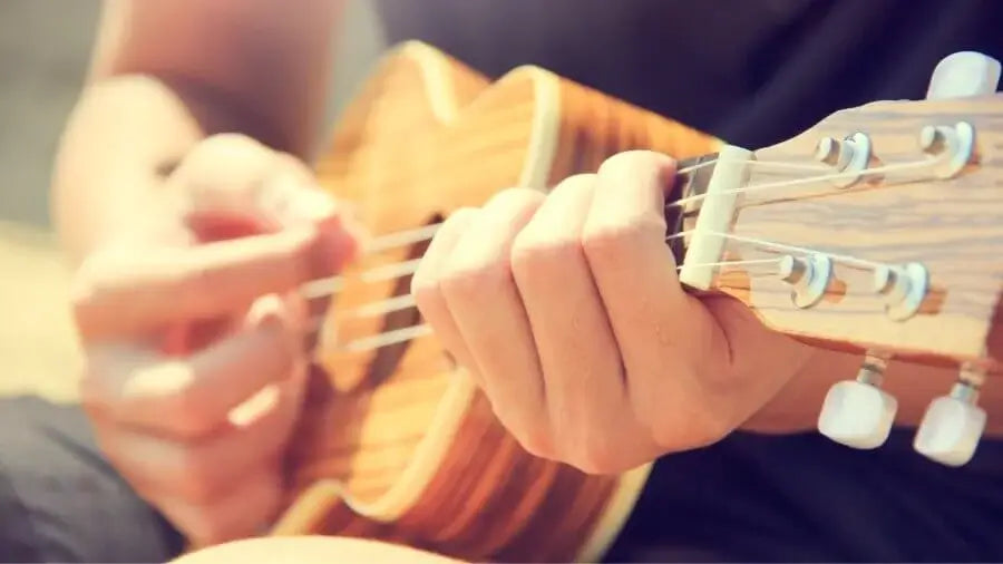 Guy picking a wooden ukulele