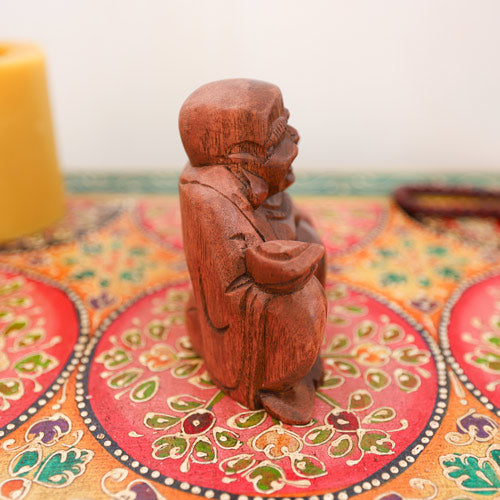 Side view of wooden laughing Buddha statue, religious decor