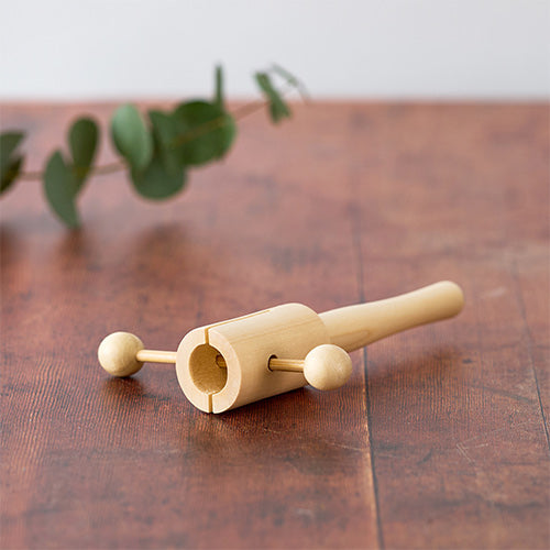 Side of Matsu T-Clacker on wooden table with green foliage