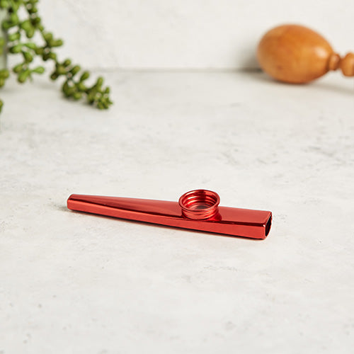 Red metal kazoo flute whistle on a white background