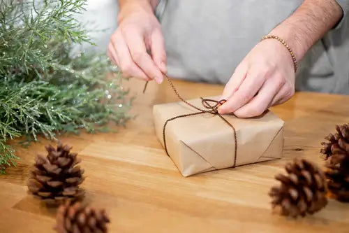 Man Packing Small Gift Package with Acorns and Christmas Tree