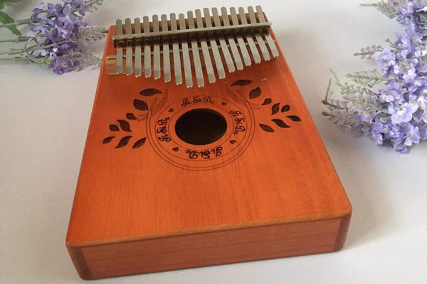 Box type plucked thumb piano kalimba instrument, with leaf carvings.