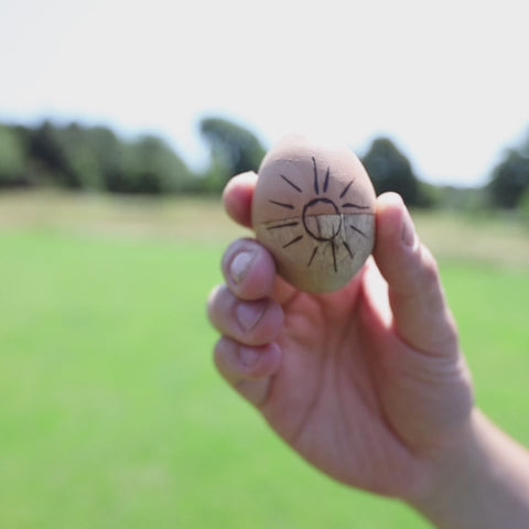 Jati Egg Shakers being shaken with greenery in the background.