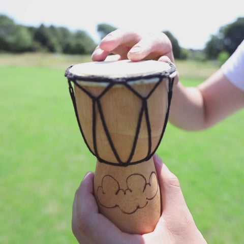 Jati Djembe drum played with greenery in the background.