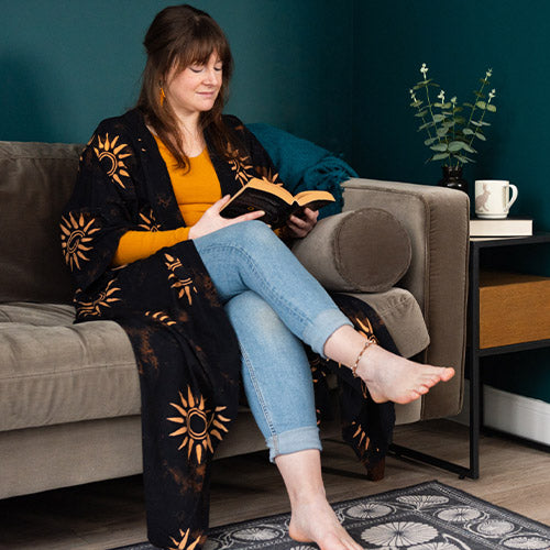 Beautiful woman in sun kimono reading a book on the sofa.